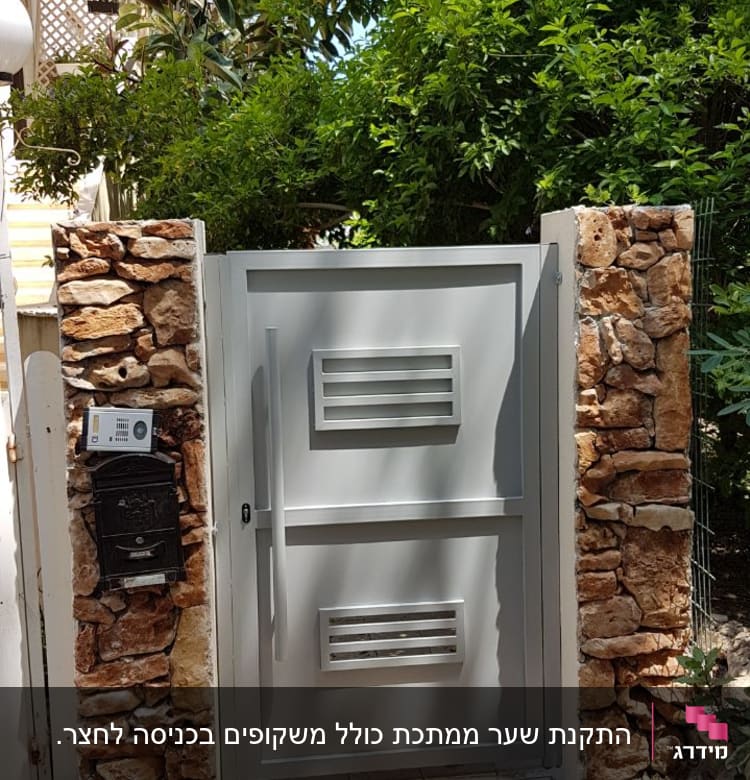 שער מתכת אפור בין עמודי אבן